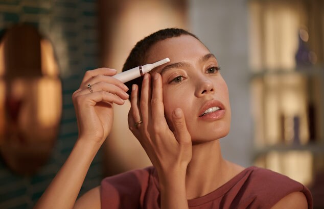 Lady shaping her eyebrows with the touch up pen trimmer