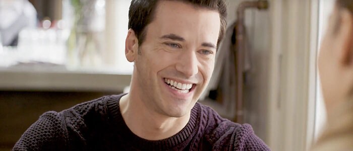 Close-up of clean-shaven smiling man in dark clothing with no trace of shaving bumps.